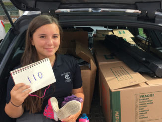 Caroline with her collection of 110 donated pairs of shoes.