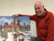 Larry with his maple syrup and a painting of the Sugar Shack by Graham Lute.