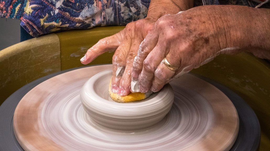 Hands work a pottery turntable. Photo by Dale Roddick.